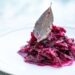 dusená červená kapusta naservírovaná na bielom tanieri s bobkovým listom. Tradičné jedlá, slovenská kuchyňa, vegánske recepty.