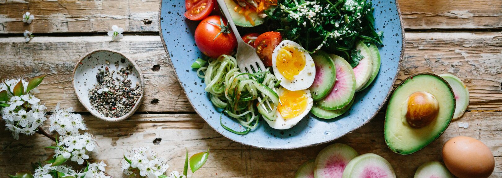 Vegetariánske recepty, vegetariánske jedlá. Miska plná zeleniny s vajcom na tvrdo, avokádom, paradajkami a listovou zeleninou.